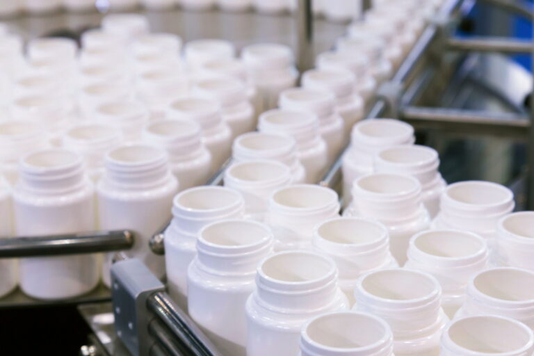 White plastic bottles on a conveyor belt in a factory.
